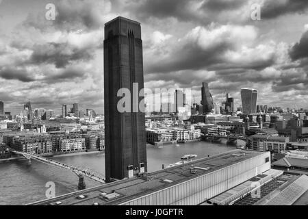 The London Skyline with the Tate Modern Tower and Millenium Bridge beside the river Thames Stock Photo