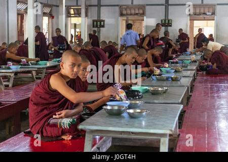 Buddhist student monks eating lunch in their dining room at the Mahagandayon Monastery Stock Photo