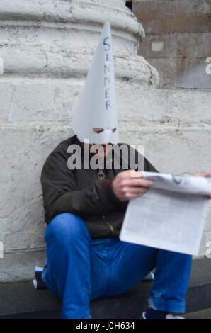 London, UK. 13th Apr, 2017. A repentant sinner in a fools hat literally sits alone and anonymous behind St Pauls Cathedral . Credit: Philip Robins/Alamy Live News Stock Photo