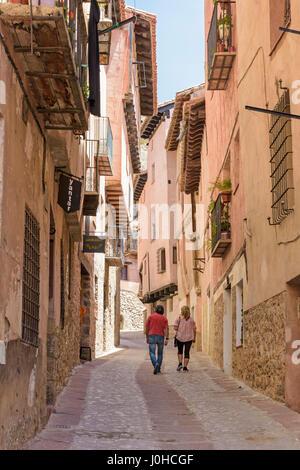A couple walk through the narrow medieval streets with balconied houses wind through the Medieval Town of Albarracin, Teruel, Aragon, Spain Stock Photo