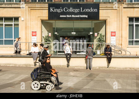 A woman in an electric wheelchair passing the entrance to King's College London, James Clerk Maxwell building, London, Waterloo, Lambeth, UK Stock Photo