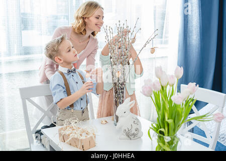 Happy mother with two children decorating willow branches with easter decorations Stock Photo