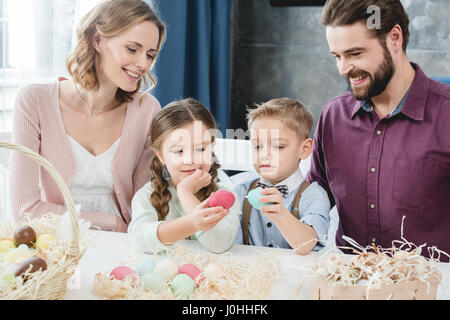 Happy family with two children sitting at table with painted easter eggs Stock Photo
