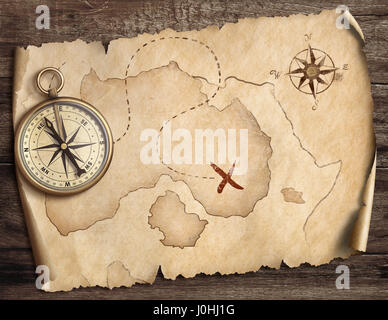 aged brass antique nautical compass on table with treasure map Stock Photo