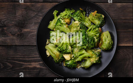 Top view of plate with roasted broccoli  on dark wooden table Stock Photo