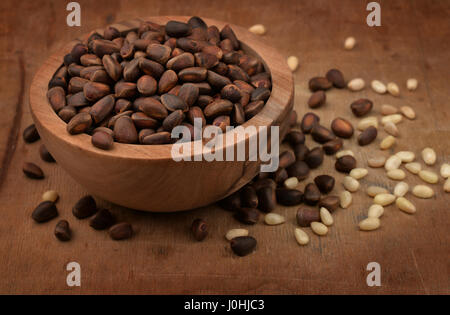 Wooden bowl of pine nuts on old wood surface Stock Photo