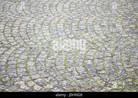 Cobbled paving, semi-circle patterns with grass growing between stones Stock Photo