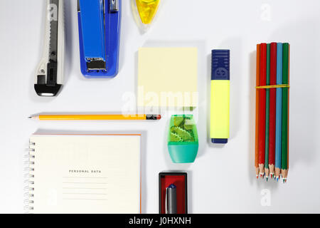 Notebook, color pencils, highlighter, memory note, pencil, binder clip, pen, sharpener, correction pen isolated on white background Stock Photo