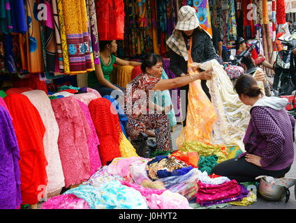 Ho chi Minh city, Viet Nam, Asia fabric market, colorful roll of cloth for clothing, Vietnamese woman choice at shop, garment industry in Vietnam