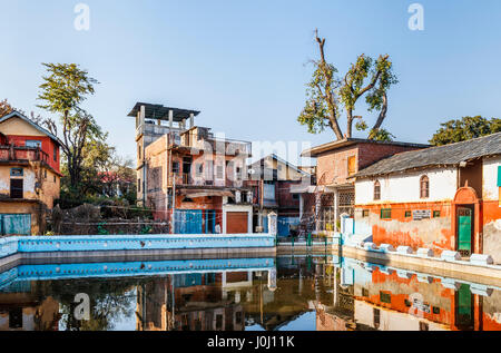 Dilapidated old buildings awaiting restoration reflected in the village tank (pond), Pragpur heritage village, Kagra district, Himachal Pradesh, India Stock Photo