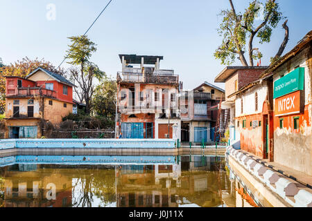 Dilapidated old buildings awaiting restoration reflected in the village tank (pond), Pragpur heritage village, Kagra district, Himachal Pradesh, India Stock Photo