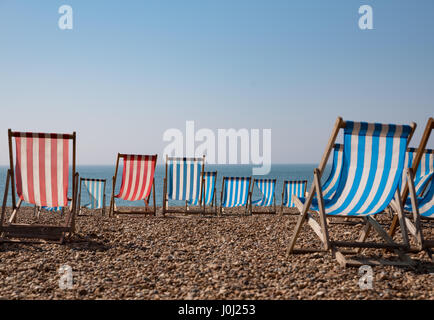 Empty traditional striped deckchairs on Brighton beach, England, UK Stock Photo