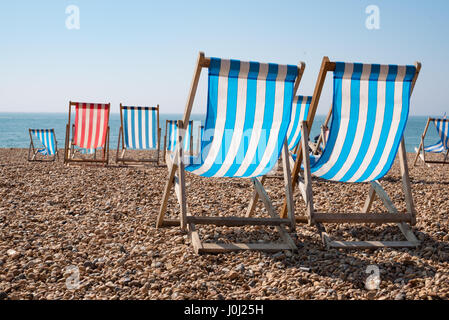 Empty traditional striped deckchairs on Brighton beach, England, UK Stock Photo