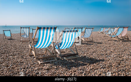 Empty traditional striped deckchairs on Brighton beach, England, UK Stock Photo