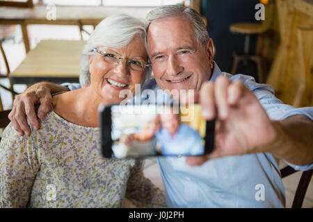 Happy senior couple taking selfie on mobile phone in cafÃƒÂ© Stock Photo