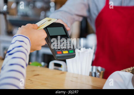 Woman making payment through credit card at counter in cafÃƒÂ© Stock Photo