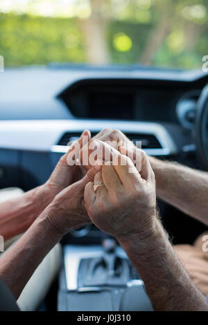 Cropped image of senior couple holding hands in car Stock Photo