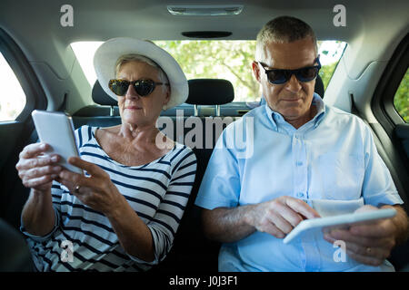 Senior couple using technologies while sitting in car Stock Photo