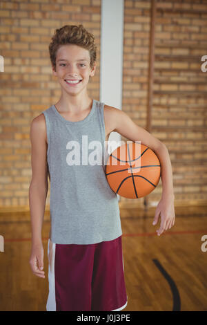 Portrait of smiling high school boy holding a basket ball in the court Stock Photo