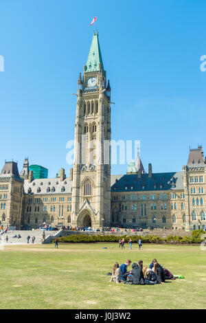 Peace Tower of Canadian Parliament Building in Ottawa. People resting on the grass in front of Canadian Parliament Centre Block. Stock Photo