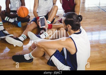 Basketball player using mobile phone while relaxing in the court Stock Photo