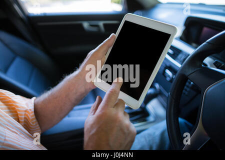 Cropped hands of man using digital tablet in car Stock Photo