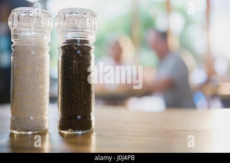 Salt and black pepper shakers on a table in cafÃƒÂ© Stock Photo