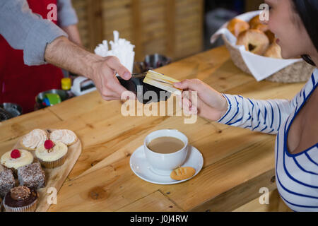 Woman making payment through credit card at counter in cafÃƒÂ© Stock Photo