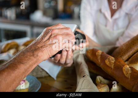 Customer making payment through NFC technology on mobile phone in cafÃƒÂ© Stock Photo