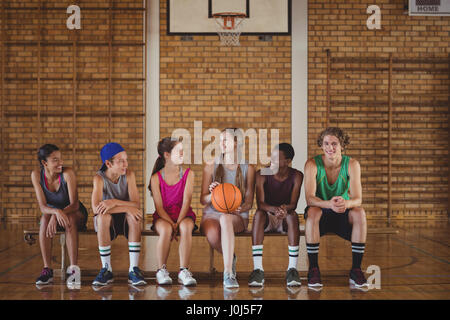 High school kids sitting on a bench in basketball court indoors Stock Photo