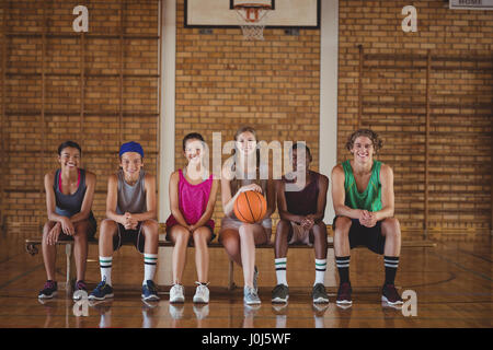 Portrait of high school kids sitting on a bench in basketball court Stock Photo