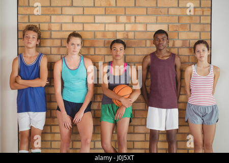 Portrait of high school kids leaning against the wall in basketball court Stock Photo