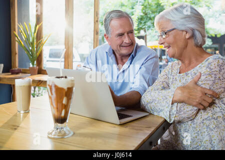 Senior couple interacting while using laptop in cafÃƒÂ© Stock Photo