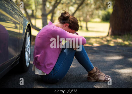 Sad woman sitting by breakdown car Stock Photo