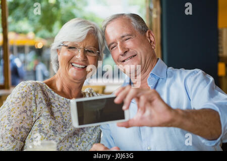 Happy senior couple taking selfie on mobile phone in cafÃƒÂ©