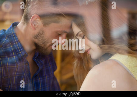 Close up of romantic couple in cafe shop seen through glass window Stock Photo