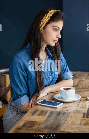 Thoughtful woman sitting at table in cafe shop Stock Photo