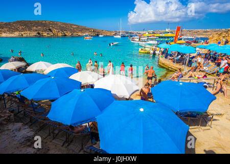 BLUE LAGOON, COMINO, MALTA - October 18, 2016: Tourists crowd to enjoy the clear turquoise water under umbrellas on a sunny day in October 18, 2016 in Stock Photo