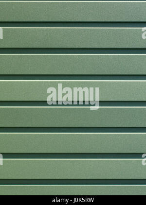 Greenery metallic fence made of corrugated steel sheet with vertical guides. Corrugated green iron sheet background close up. Stock Photo