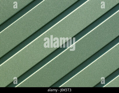 Greenery metallic fence made of corrugated steel sheet with vertical guides. Corrugated green iron sheet background close up. Stock Photo