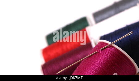 Shallow depth of field close up on sewing cotton reels and a needle, isolated on white background Stock Photo