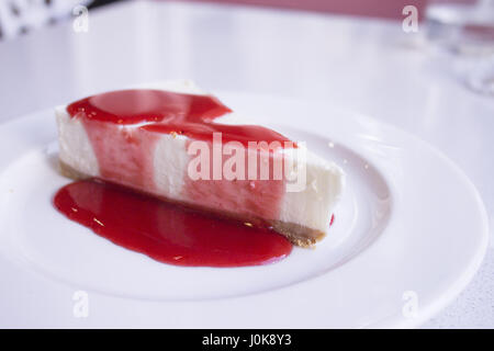 White plate with cheese cake with strawberry syrup Stock Photo