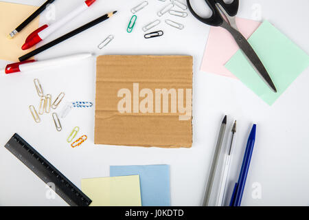 Scissors pen pencil sticker paper clips and cardboard lie on a white table. View from above Stock Photo