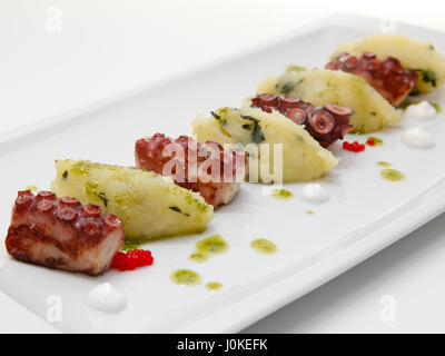 Close up of grilled octopus appetizer with small potatoes on plate. Selective focus, shallow DOF Stock Photo