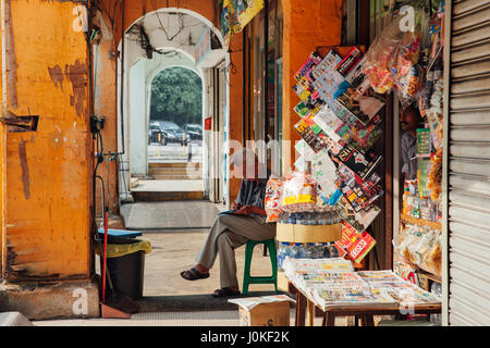 Kuala Lumpur, Malaysia - March 17, 2016:  Vendor sitting before his shop in Chinatown, Kuala Lumpur, Malaysia on March 17, 2016. Stock Photo