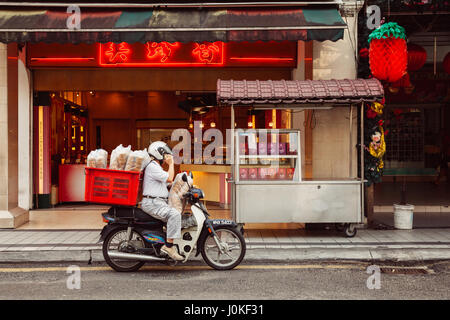 Kuala Lumpur, Malaysia - March 17, 2016:  Man delivering supplies to Chinese restaurant in Chinatown, Kuala Lumpur, Malaysia on March 17, 2016. Stock Photo