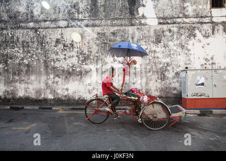 George Town,  Malaysia - March 21, 2016: Cycle rickshaw is riding down the street on March 21, 2016 in George Town, Penang, Malaysia. Stock Photo