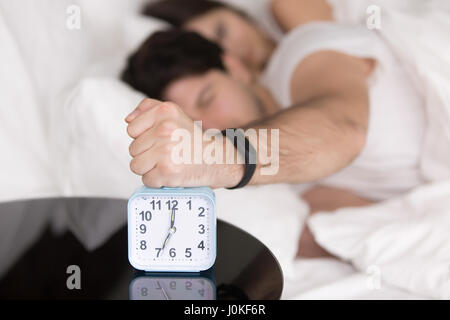 Couple waking up early, guy turning off annoying alarm clock Stock Photo