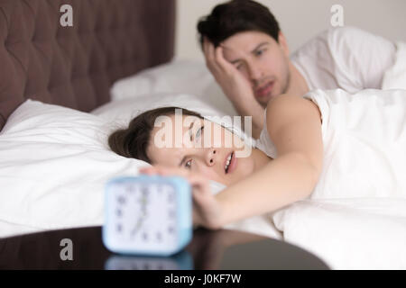 Couple turning off or snoozing alarm clock, waking up problem Stock Photo