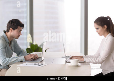 Male office worker angrily looking at young female colleague, ri Stock Photo
